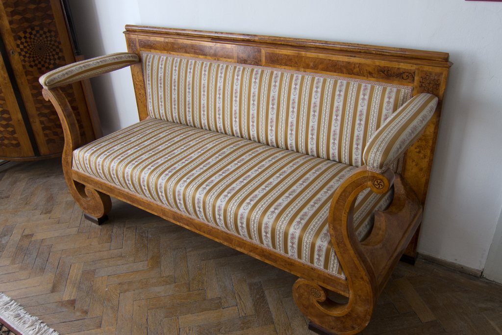 Antique striped sofa with a carved wooden frame on a herringbone parquet floor